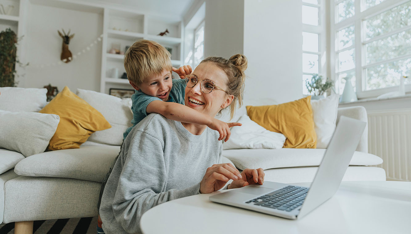 Sohn umarmt Mutter vor Laptop