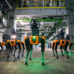 Mehrere Roboterhunde mit orangefarbenen Akzenten im Kraftwerk Simmering.