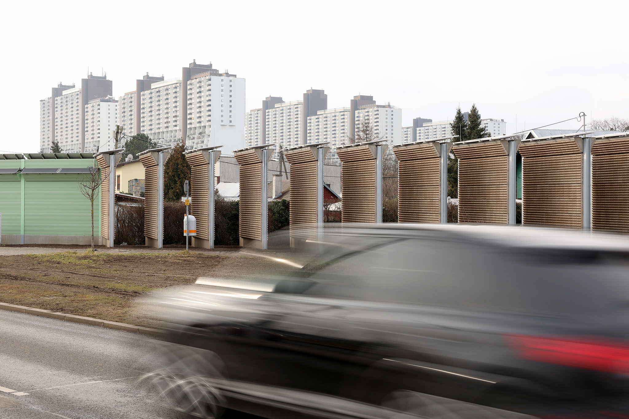 Ein schwarzes Auto rast an der PV-Lärmschutzwand vorbei.