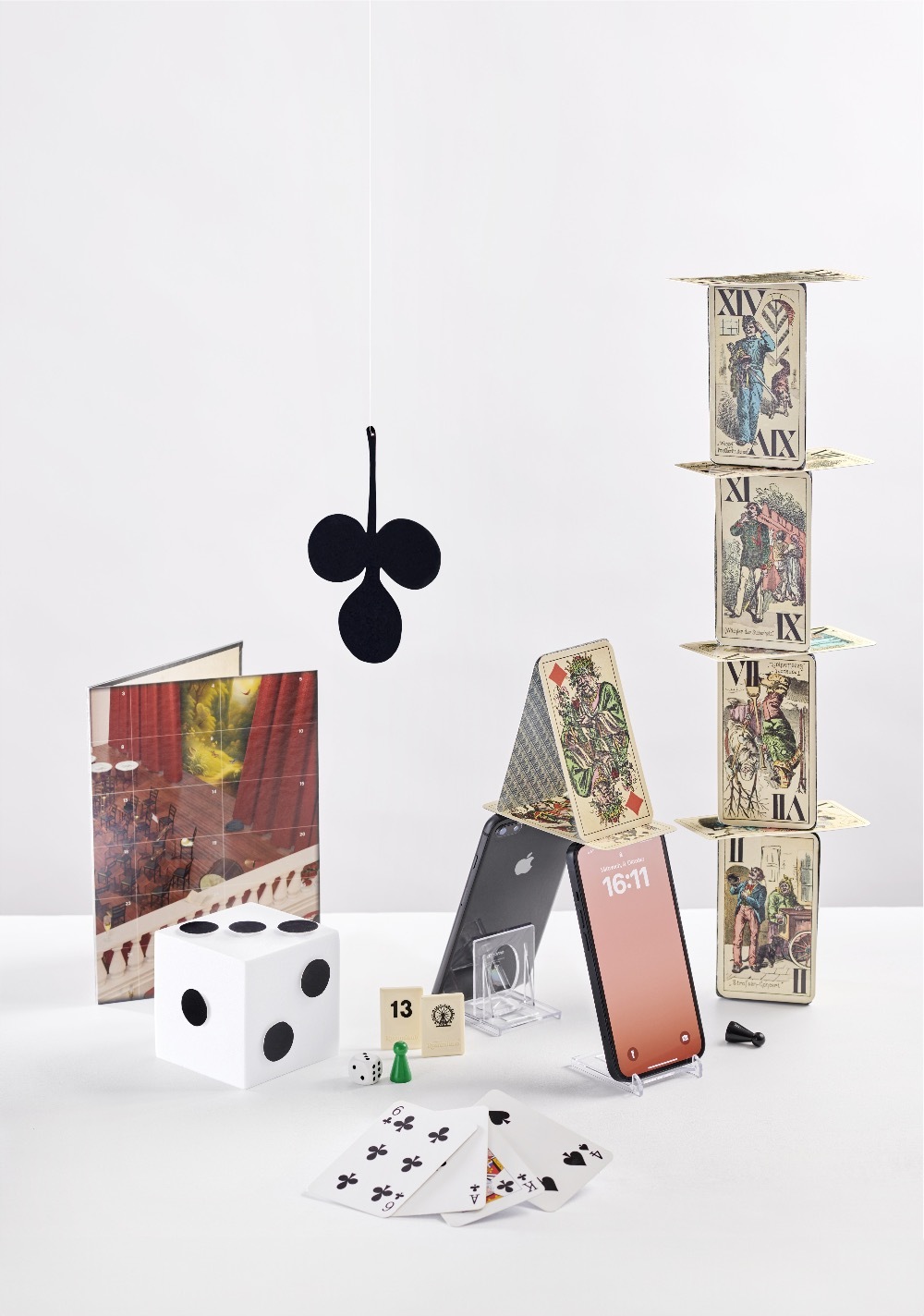 Piatnik Karten angeordnet zu einem Turm mit iPhones als Basis. Verschiedene Spieleutensilien von der Firma Refurbed