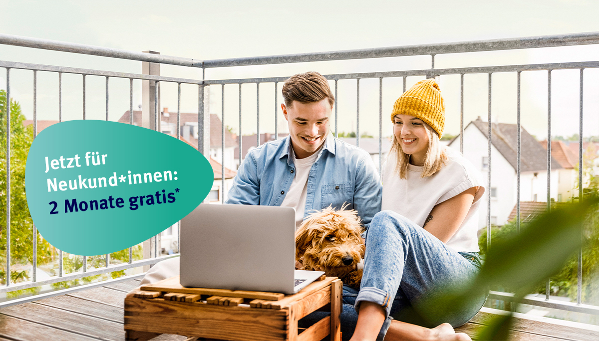Ein lächelndes Paar mit Hund benutzt einen Laptop auf einem Balkon; ein Schild verspricht „2 Monate gratis“ für Neukunden.