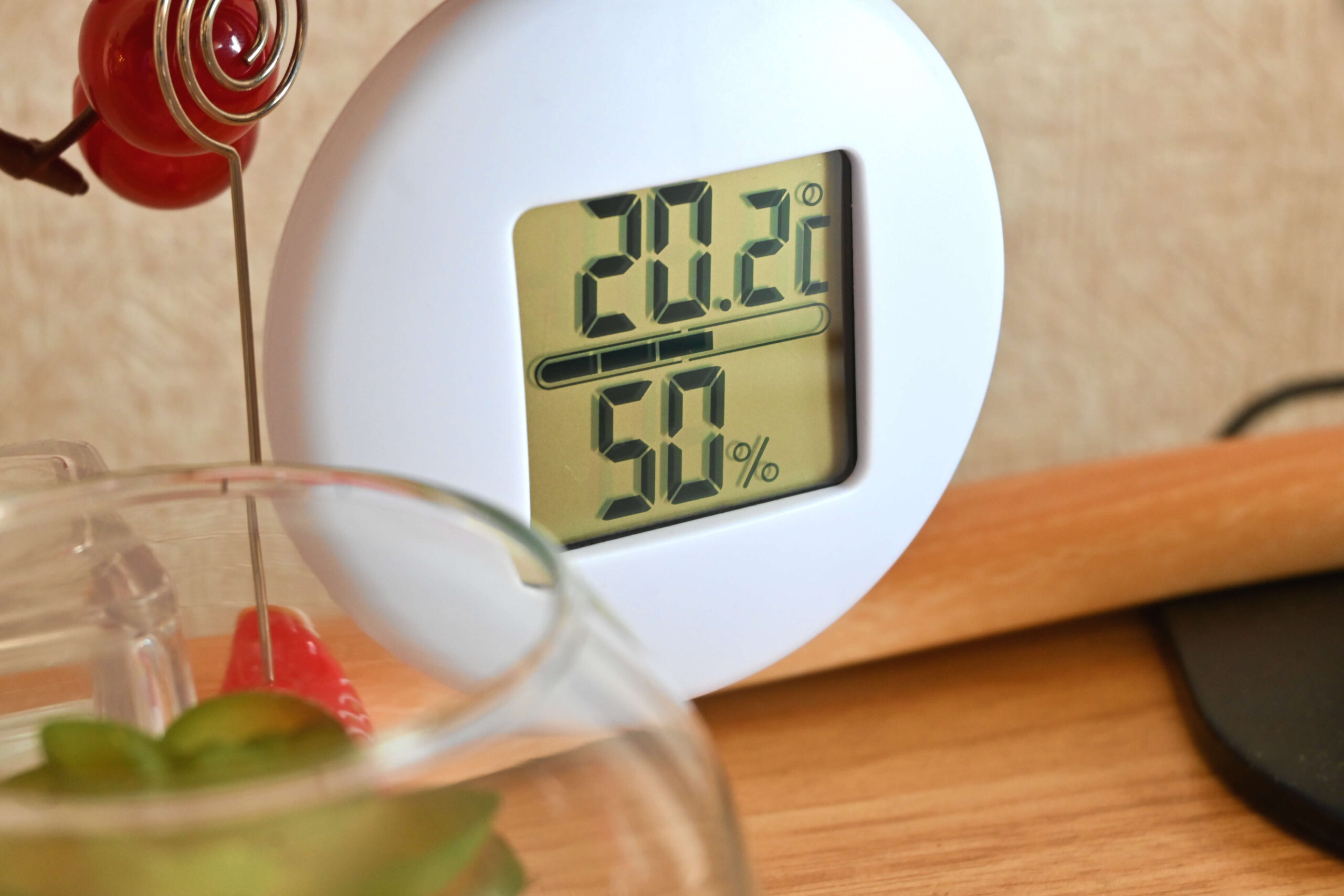 Eine Digitalanzeige zeigt 20,2 °C Temperatur und 50 % Luftfeuchtigkeit auf einer Holzoberfläche an.
