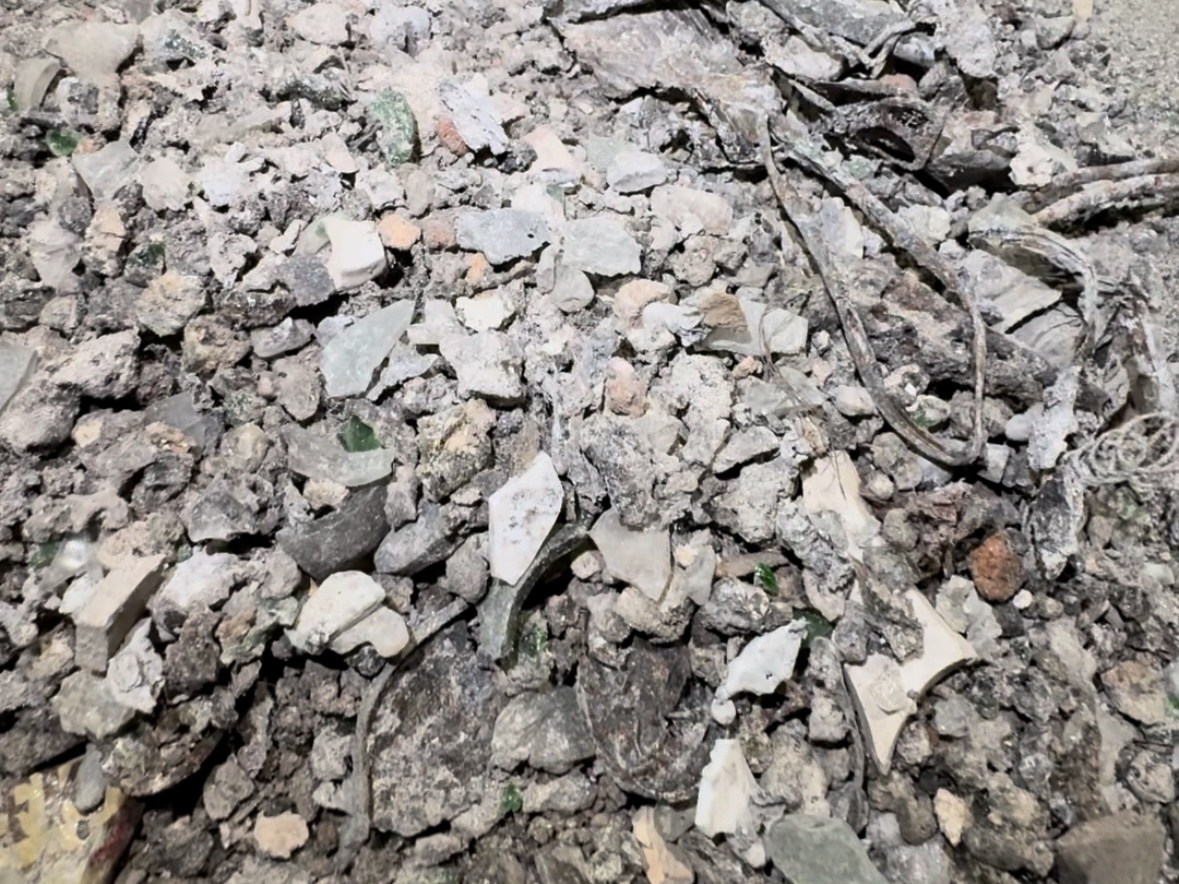 Eine Nahaufnahme eines Haufens aus zerbrochenem Beton, Schlacke, Schutt und Trümmern, die verstreut auf dem Boden liegen.