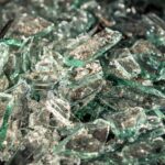 Nahaufnahme von zerbrochenen Glassplittern, die verstreut auf einem Haufen liegen, das Licht reflektieren und gezackte Kanten aufweisen.