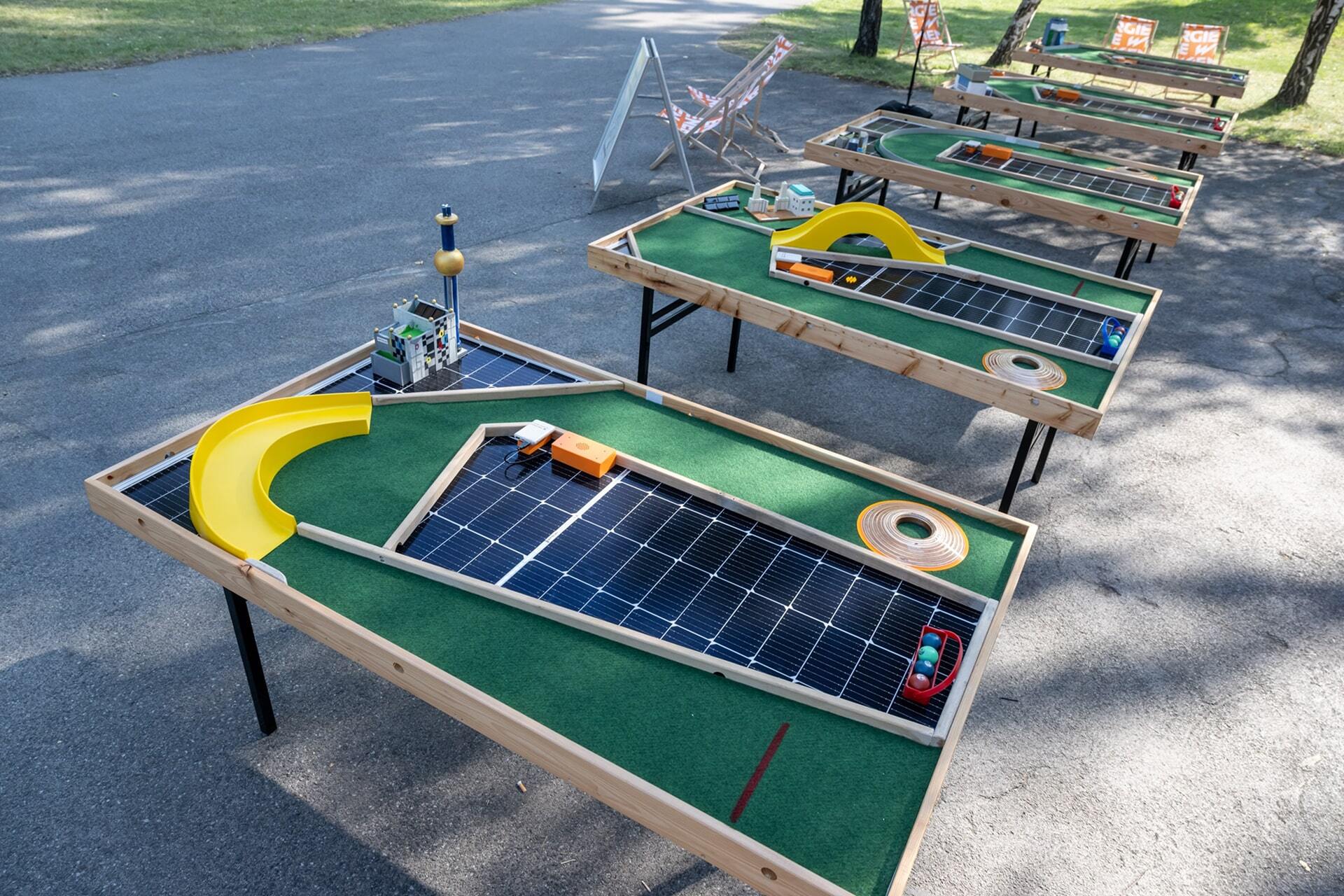 Minigolftische aus alten Solarpanelen mit Hindernissen, die im Freien auf einer Asphaltfläche aufgestellt sind.