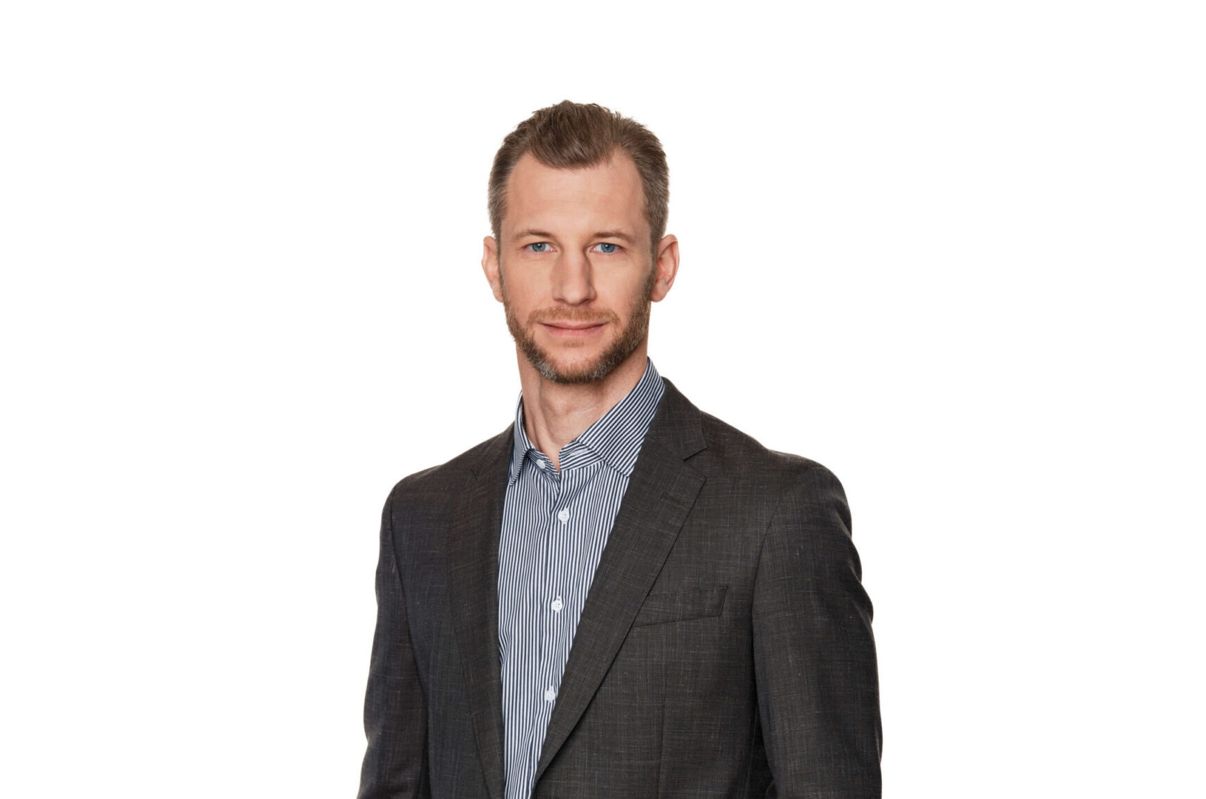 Pressesprecher Martin Meyath, in grauer Anzugsjacke und gestreiftem Hemd, steht selbstbewusst vor einem schlichten weißen Hintergrund.