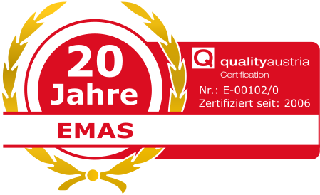 Auf dem rot-goldenen Abzeichen steht „20 Jahre EMAS“, rechts davon sind die Angaben zur „qualityaustria“-Zertifizierung zu sehen.