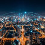 Nächtliche Luftaufnahme einer Stadtsilhouette, überlagert von einer leuchtenden digitalen Netzwerkkarte.