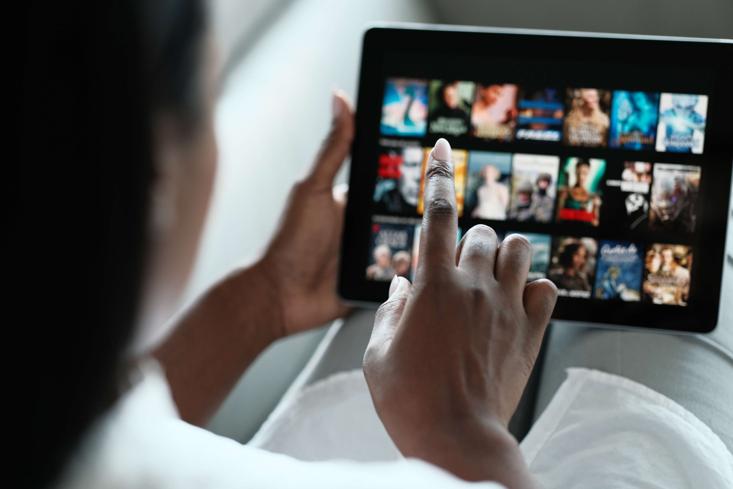 Eine Person, die mit dem Finger durch ein Video-Streaming-Menü auf einem Tablet scrollt.