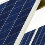 Nahaufnahme von schräg ausgerichteten Solarmodulen vor einem klaren Himmel. Die Photovoltaikzellen sind deutlich zu erkennen.